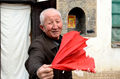 老大爷在自家院子里把手中红绸子一甩变一把雨伞。 (图：赵晨 / 文：王力立)